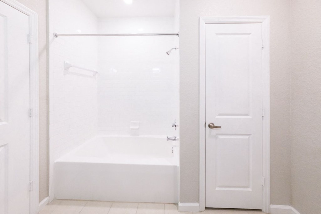 a white bathroom with a tub and a closet at Linden on the GreeneWay, Orlando