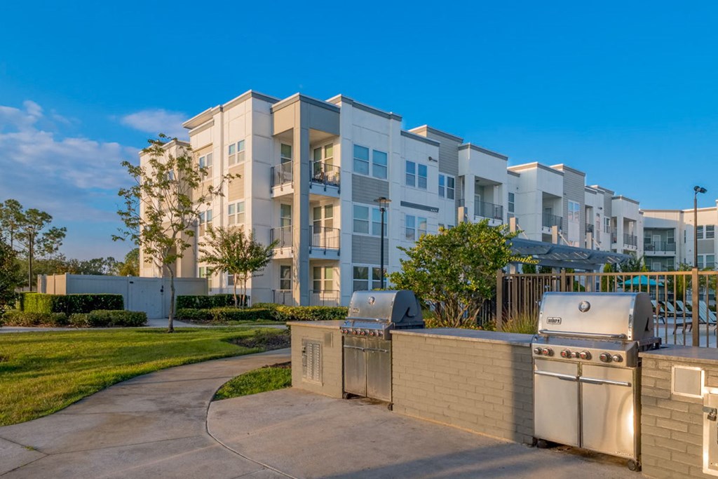 a large apartment building with a grill and a sidewalk at Linden on the GreeneWay, Orlando, 32824