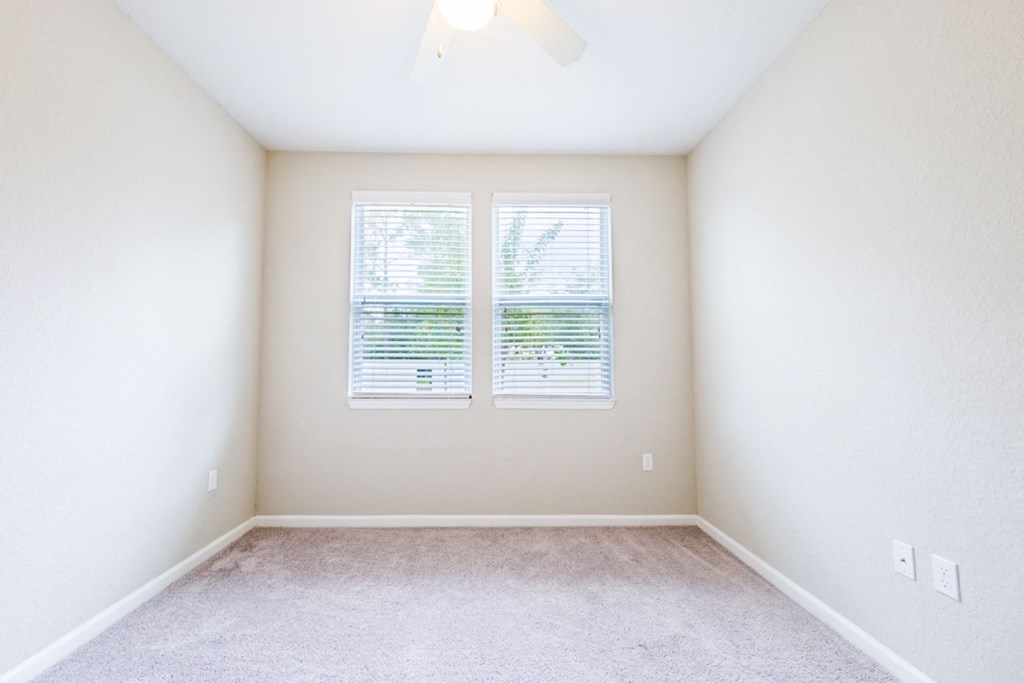 an empty room with two windows and a carpeted floor at Linden on the GreeneWay, Florida