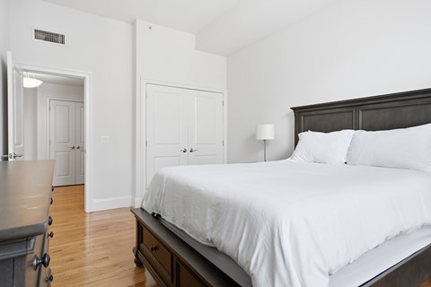 A bedroom with a bed, nightstand, and a dresser.