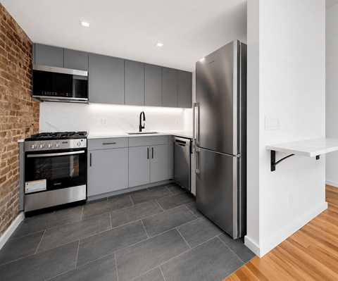A modern kitchen with a stainless steel refrigerator and oven.