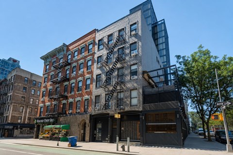 A modern building with a glass facade is situated next to a traditional brick building with a fire escape.