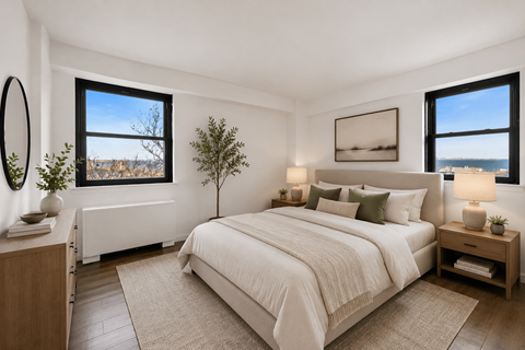 A bedroom with a large bed, a nightstand, and a window overlooking the ocean.