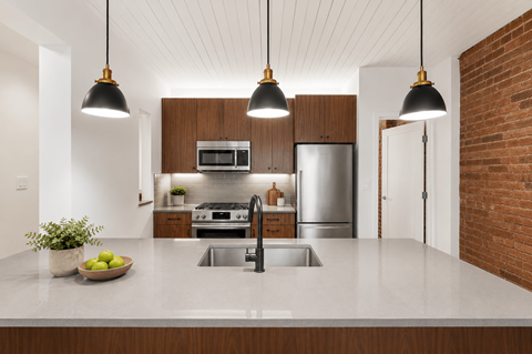 A modern kitchen with a large island and pendant lights.