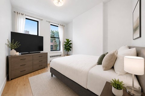 A bedroom with a bed, a dresser, and a window.