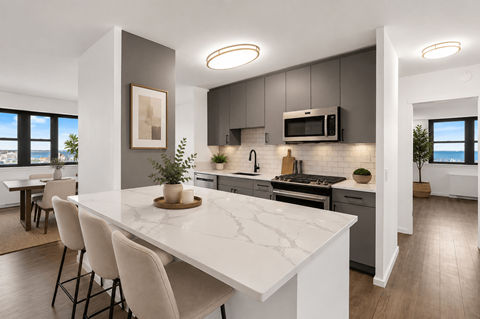 A modern kitchen with a marble countertop and white chairs.