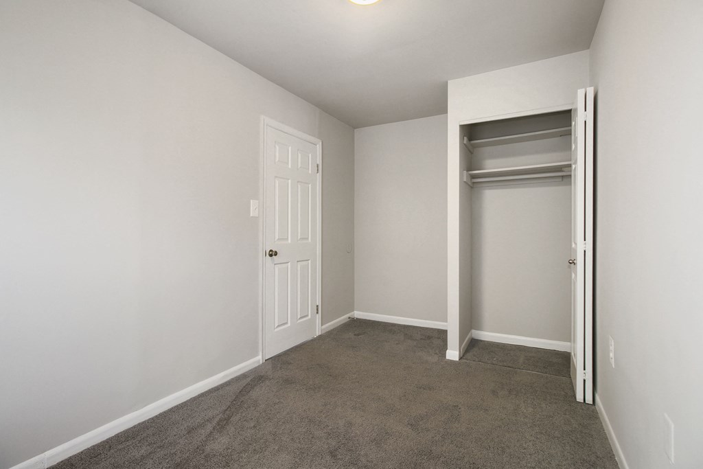an empty bedroom with a closet and an open door
