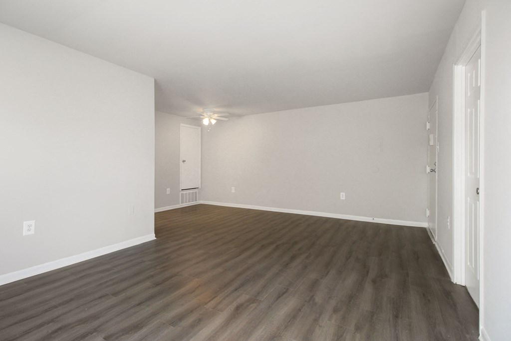 an empty living room with wood floors and white walls