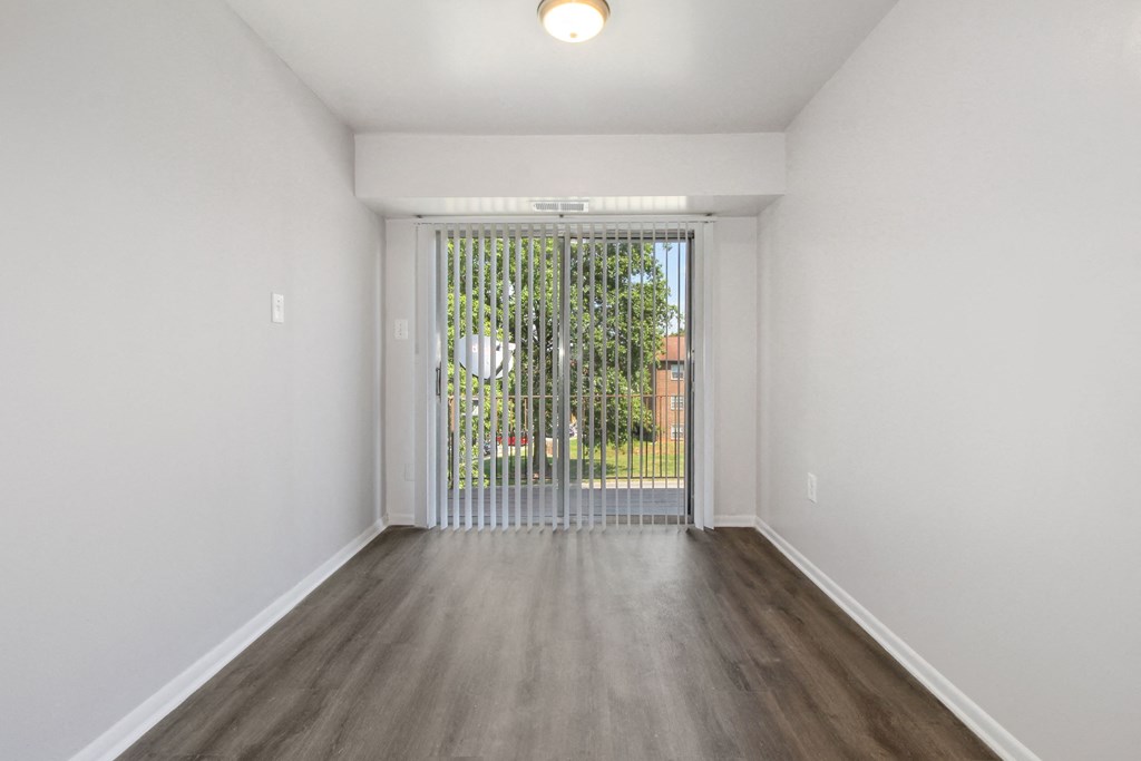 an empty living room with a sliding glass door to a yard