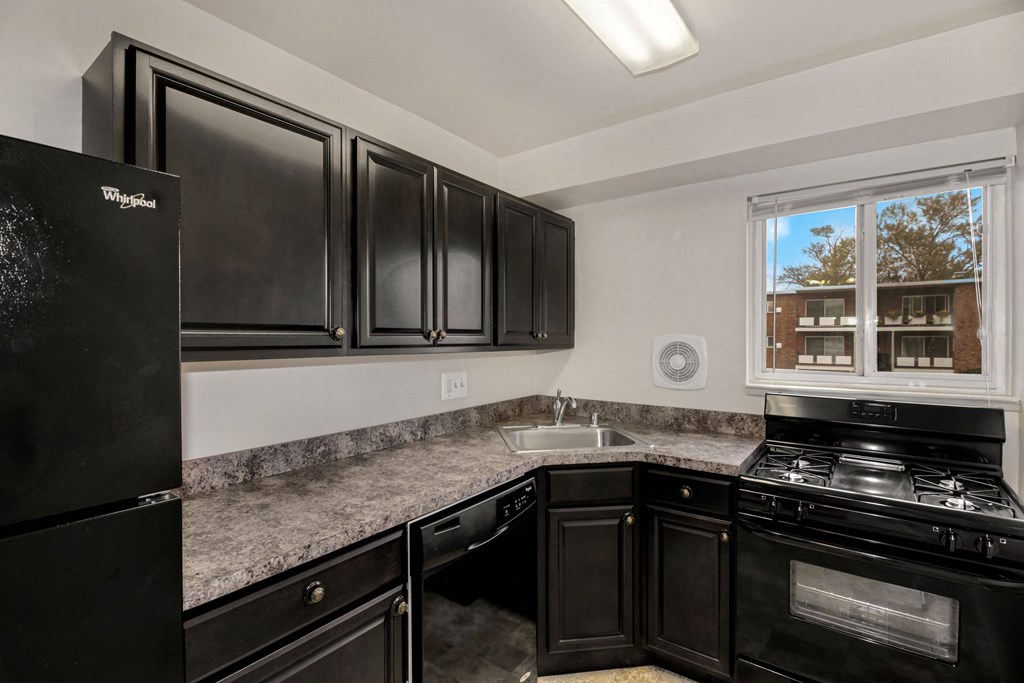 Kitchen with a refridgerator, gas stove and dark cabinets