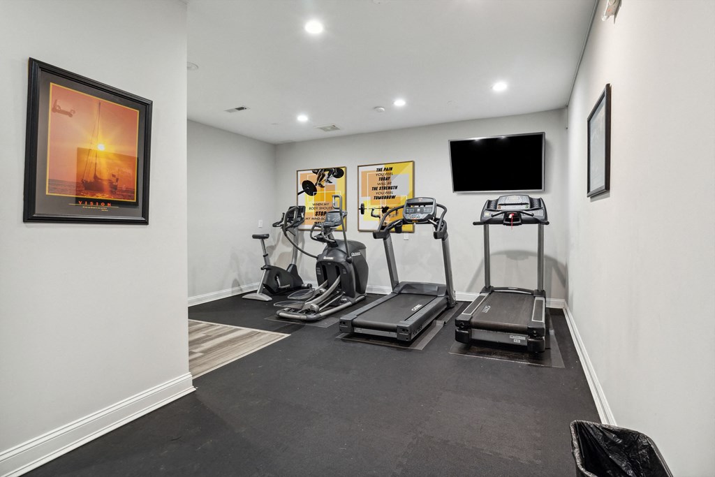 a gym with treadmills and a tv on the wall