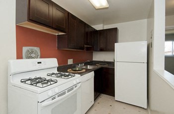 Kitchen with dark cabinets and white refridgerator, oven and dishwasher at Laurel Pines Apartments in Laurel, MD Kitchen with dark cabinets and white appliances - Photo Gallery 2
