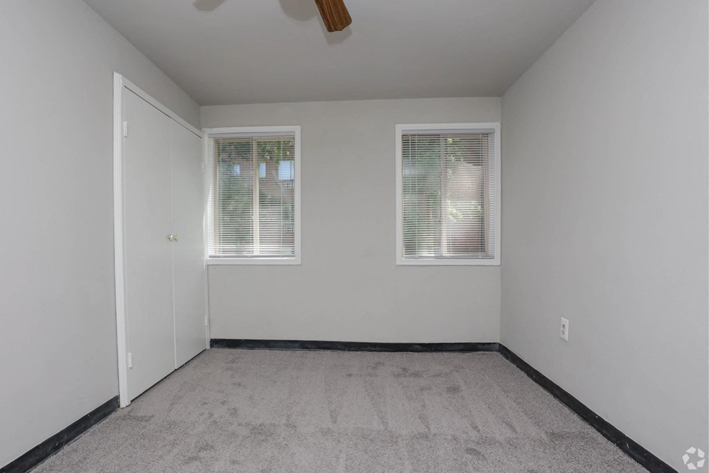 Unfurnished bedroom with two windows, gray walls and carpeting, and a ceiling fan