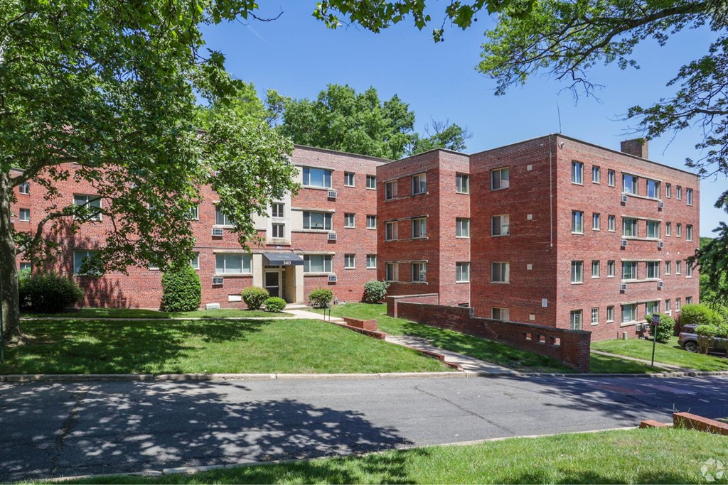 Outdoor view of the apartment building on a sunny day with blue skies and full trees