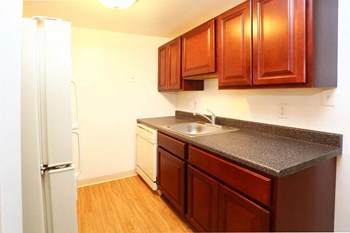 Kitchen with wood cabinets, granite-like countertops, and dishwasher at The Glen Apartments in Falls Church, VA Kitchen with wood cabinets, granite-like countertops, and dishwasher - Photo Gallery 2