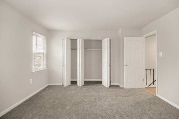 an empty living room with white doors and a carpeted floor