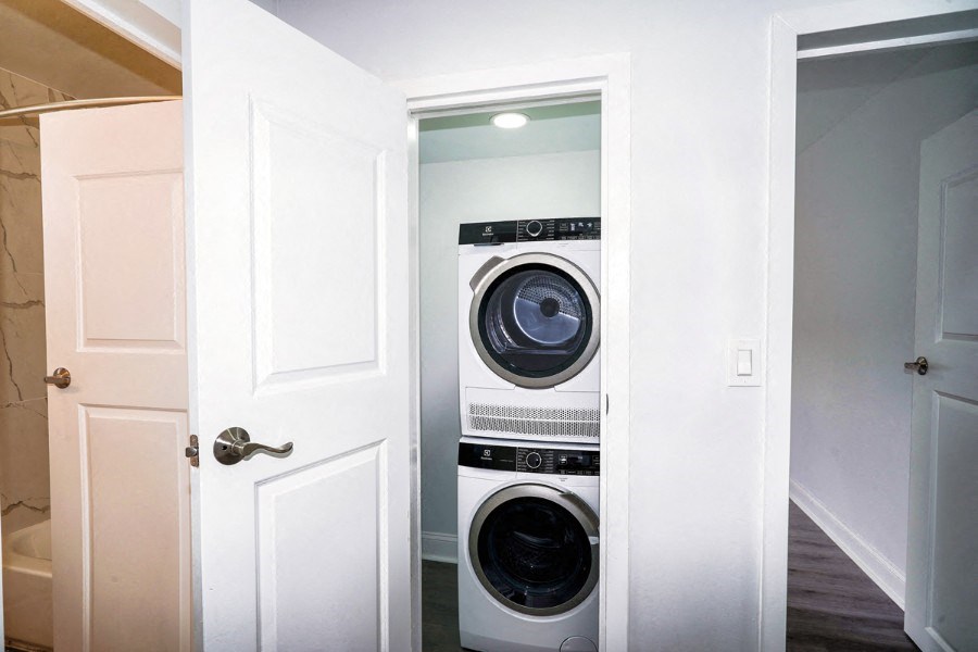 An open closet has a stacked washer and dryer inside