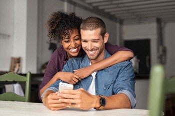 couple smiling and looking at a cell phone