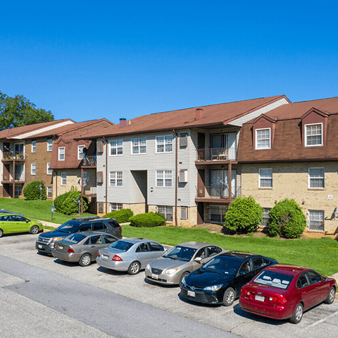 an apartment building with a parking lot full of cars