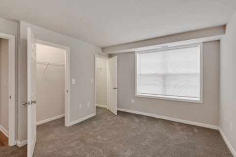 an empty bedroom with a closet and a window