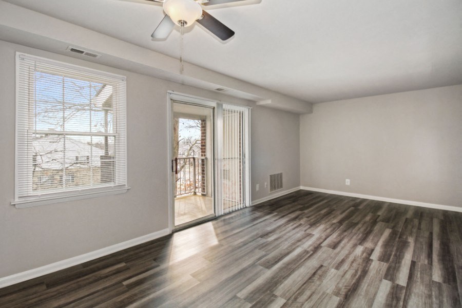 an empty living room with a window and a ceiling fan