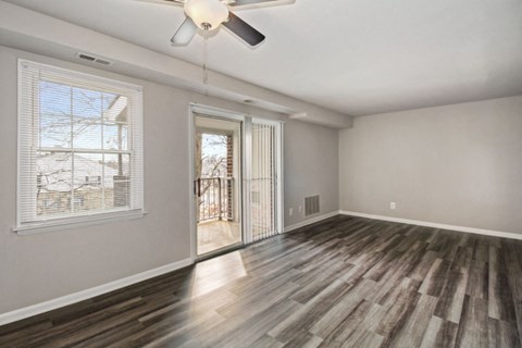 an empty living room with a window and a ceiling fan