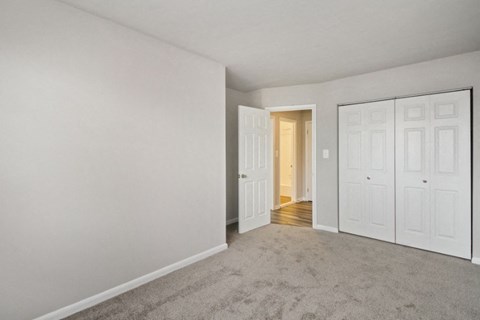 an empty living room with white doors and a door to a hallway