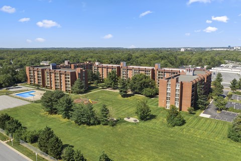 A large red brick building with a pool in the front yard.