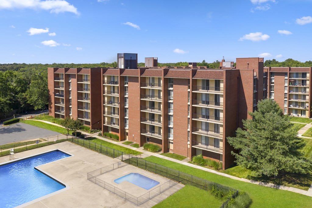 A large brick apartment building with a pool in front.