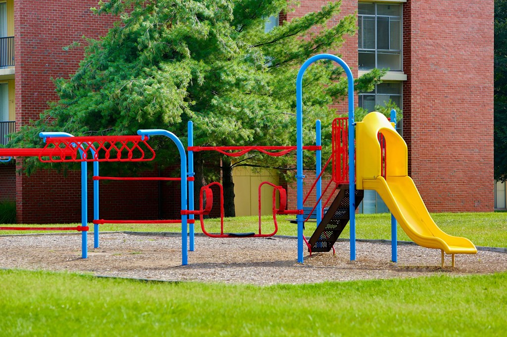 A playground with a yellow slide and red and blue play equipment.