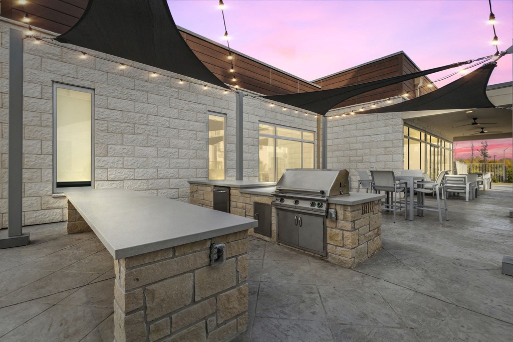 Resident outdoor patio area with a grill and a table with chairs at LynnCora, Grand Prairie