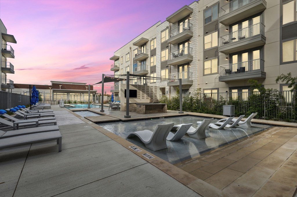 pool with lounge chairs in front of an apartment building at LynnCora, Texas