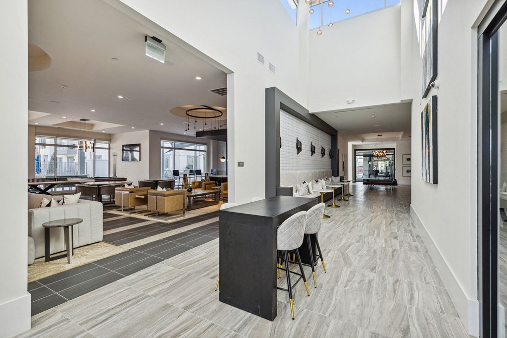 a large resident lounge lobby with tables and chairs and a bar with chairs at LynnCora, Grand Prairie, TX, 75052
