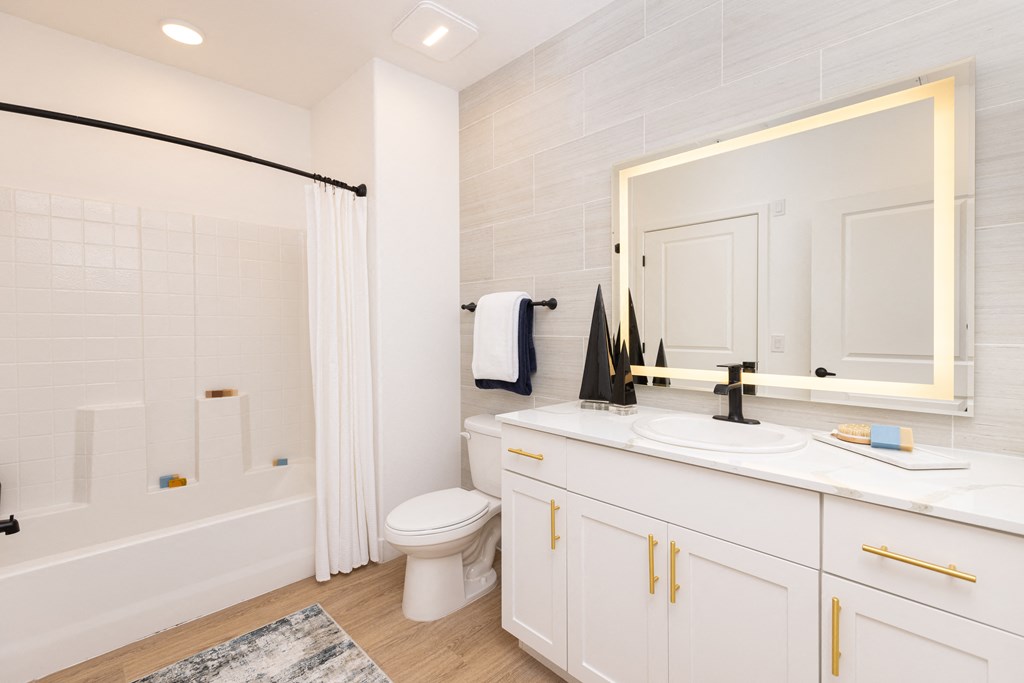 large bathroom with shower and tub and backlit mirror