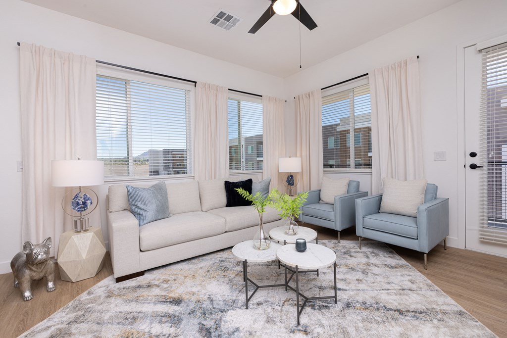 spacious living room with large windows and a ceiling fan