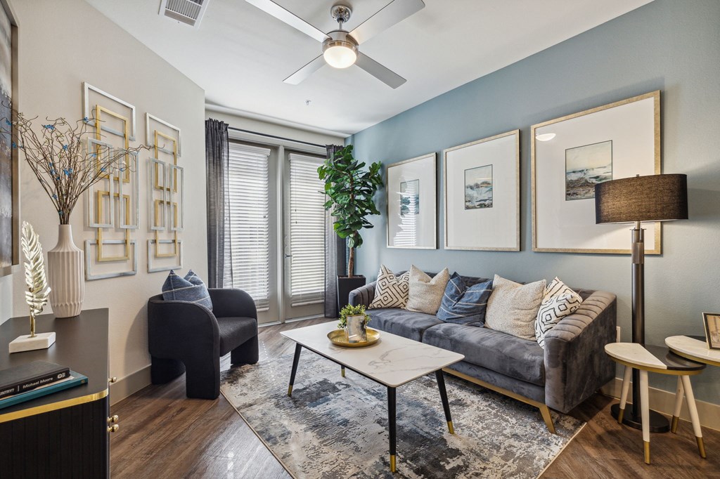 Model apartment living room area with ceiling fan and large window at LynnCora, Grand Prairie, TX, 75052