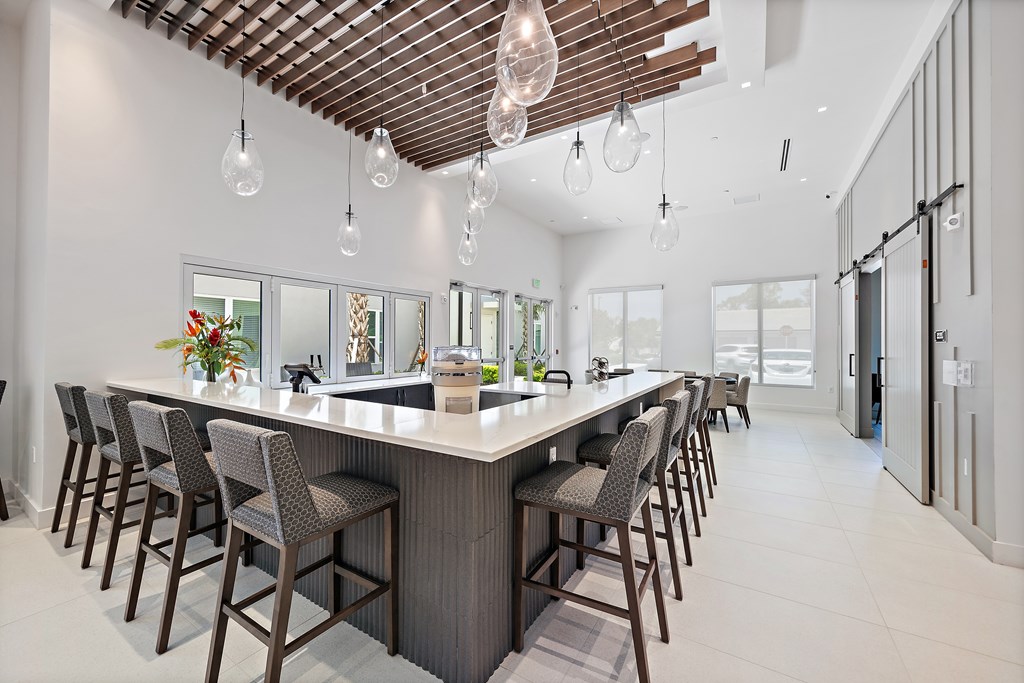 A modern kitchen with a long bar and chairs. at Mira at Palmer Ranch, Sarasota, FL