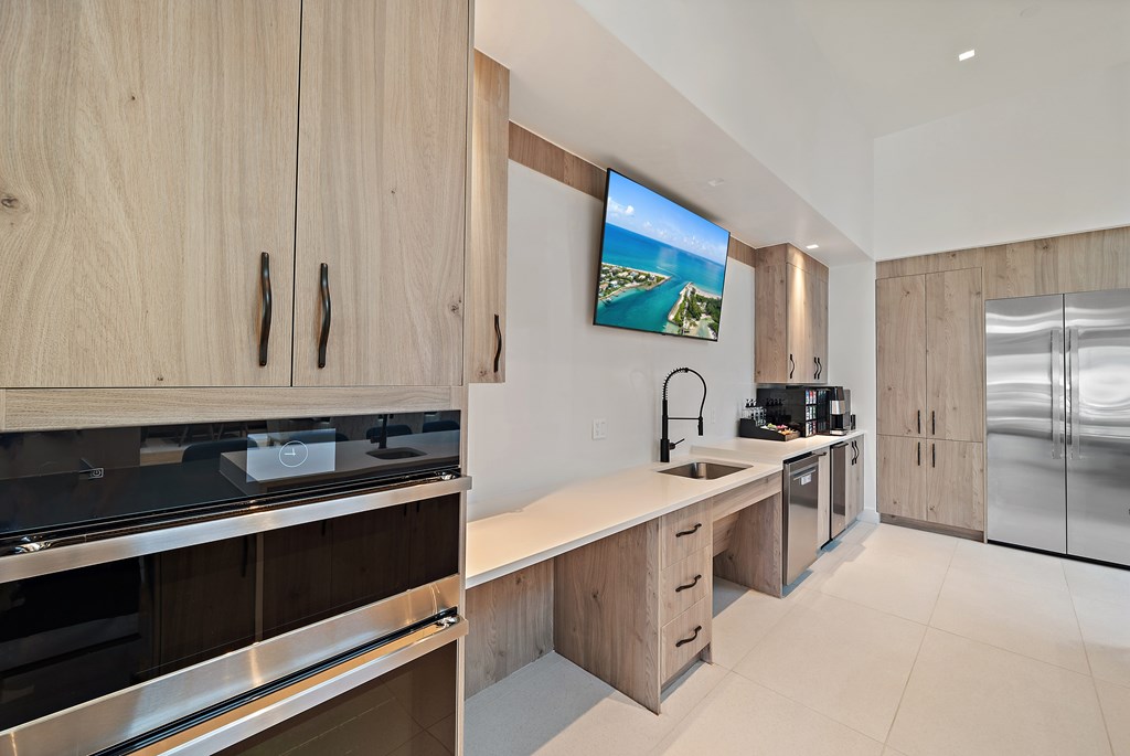 A modern kitchen with wooden cabinets and a flat screen TV mounted above the counter. at Mira at Palmer Ranch, Florida, 34238