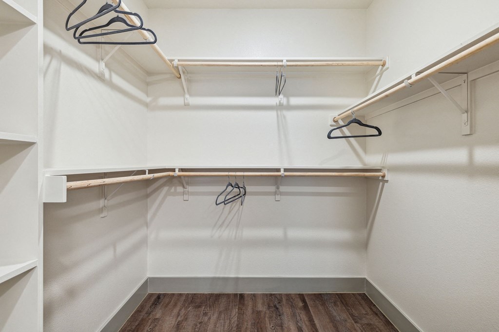 a spacious walk in closet with white walls and wood flooring at LynnCora, Grand Prairie, TX, 75052