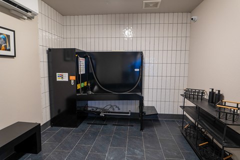 A black fridge in a room with a black bench and a black shelf.