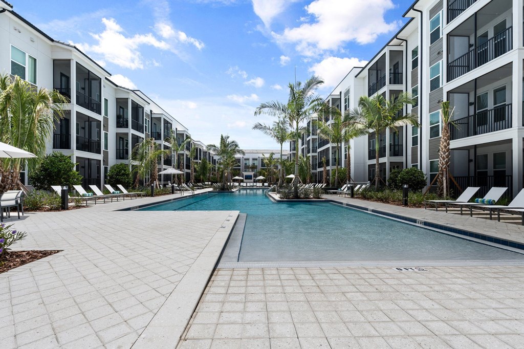 a large swimming pool in courtyard with Mira at Palmer Ranch Apartment buildings around it