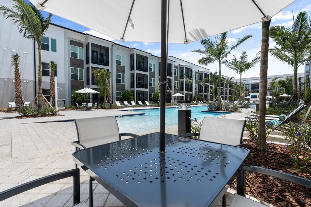 a patio with a table and chairs in front of an apartment building