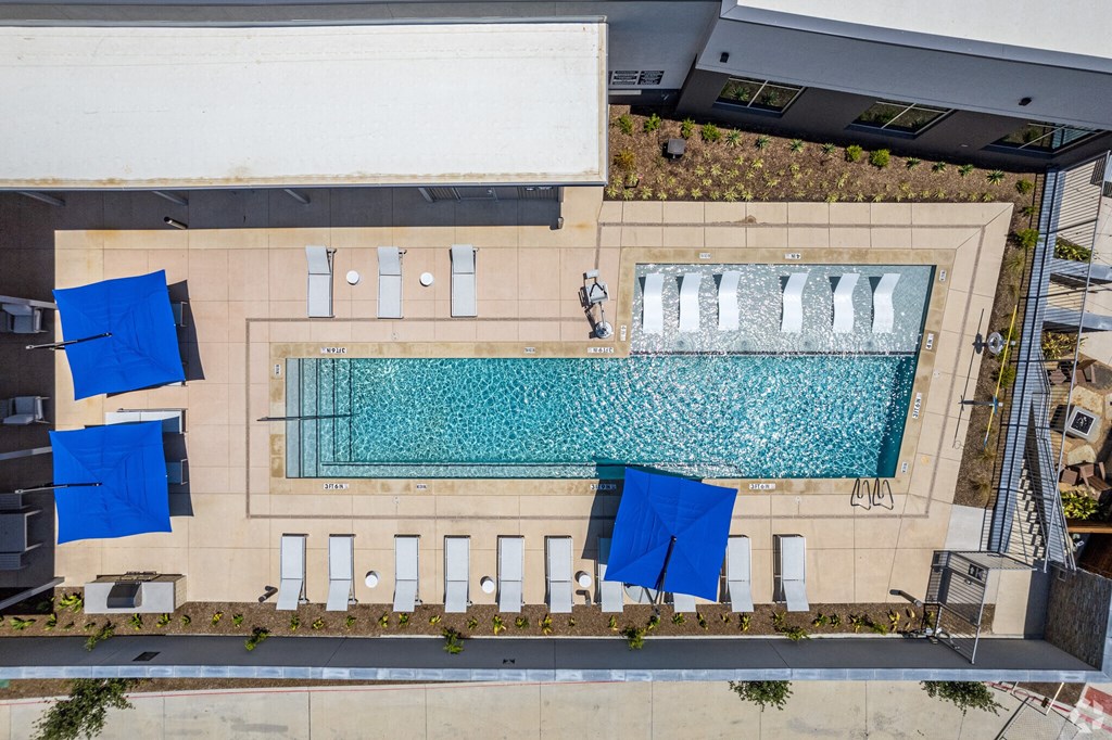 Ironcrest apartments view of the pool from above with blue umbrellas on a sunny day