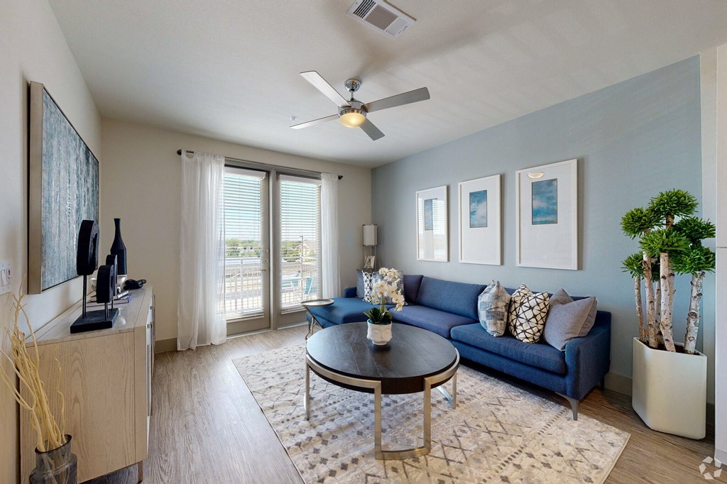 a living room with a blue couch and a coffee table in front of a large glass door