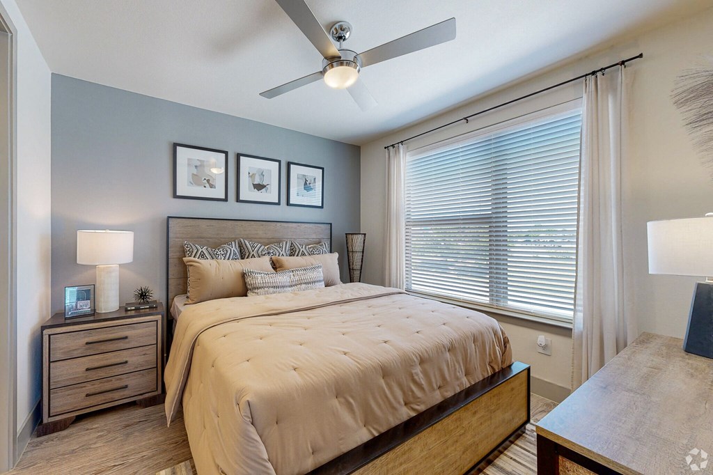 a bedroom with a large window and a ceiling fan