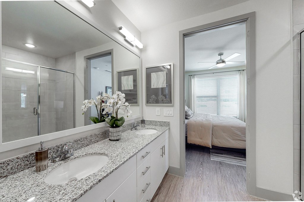 Ironcrest model apartment bathroom with double sinks looking into the bedroom area