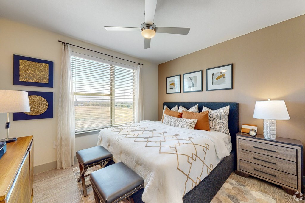 Ironcrest model apartment bedroom with large window and ceiling fan