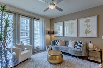 a living room with a ceiling fan and large windows at LynnCora in Grand Prairie, TX