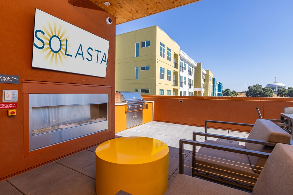 a patio with a grill and a yellow table and chairs