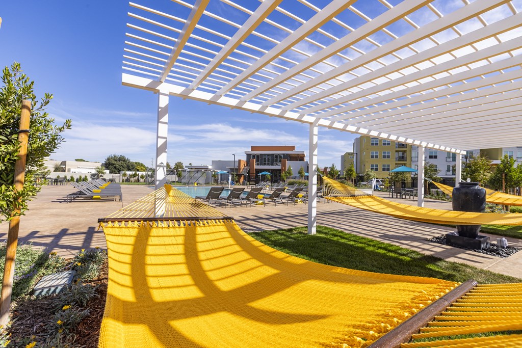 a group of yellow hammocks under a white shad at Solasta apartmentse